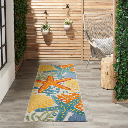 Outdoor balcony with wooden slat screen, hanging planters, wicker chair, stump table, and an 8' runner rug with a yellow, blue and orange starfish pattern.