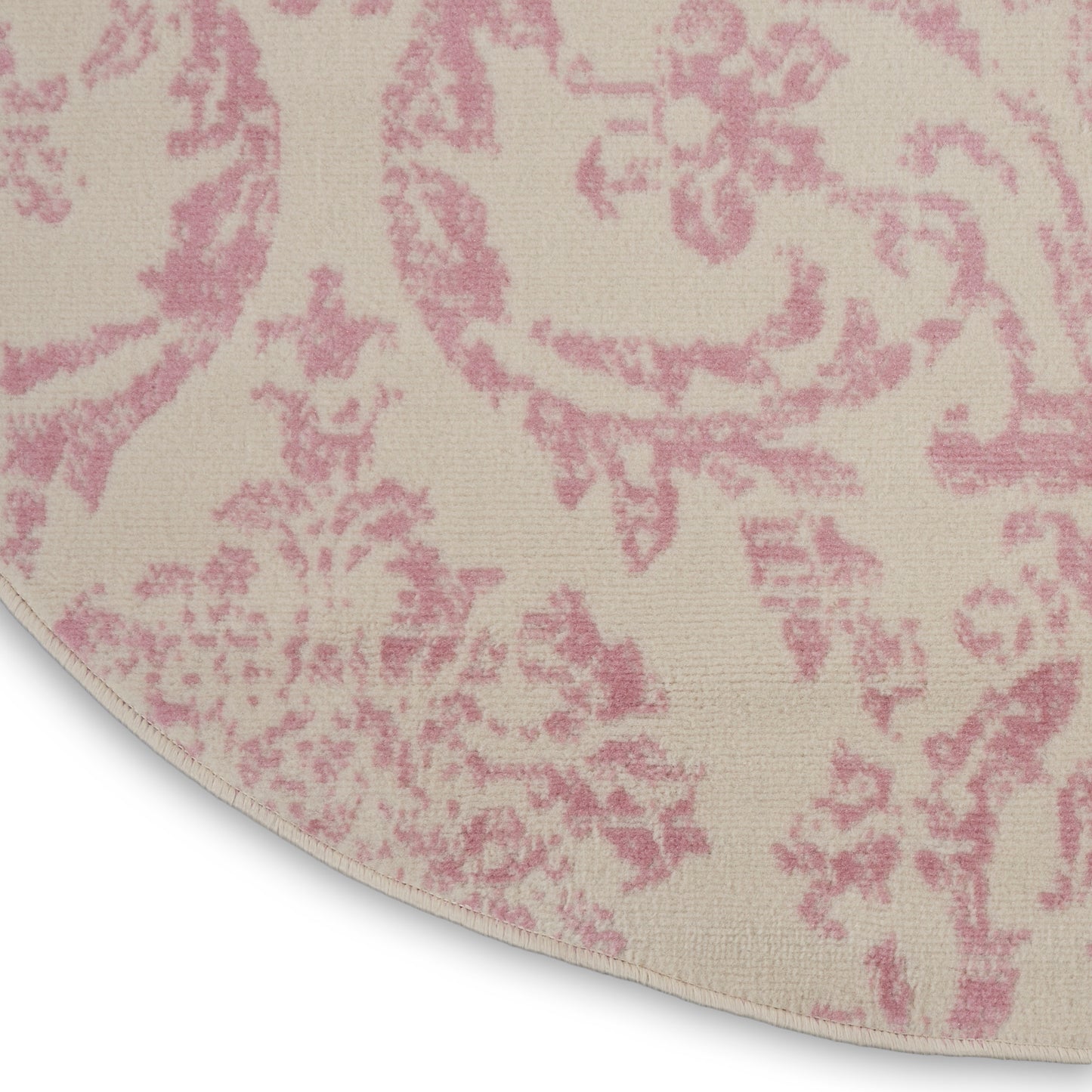 Round cream rug with pink damask pattern; woven textile, oriental-style area rug.