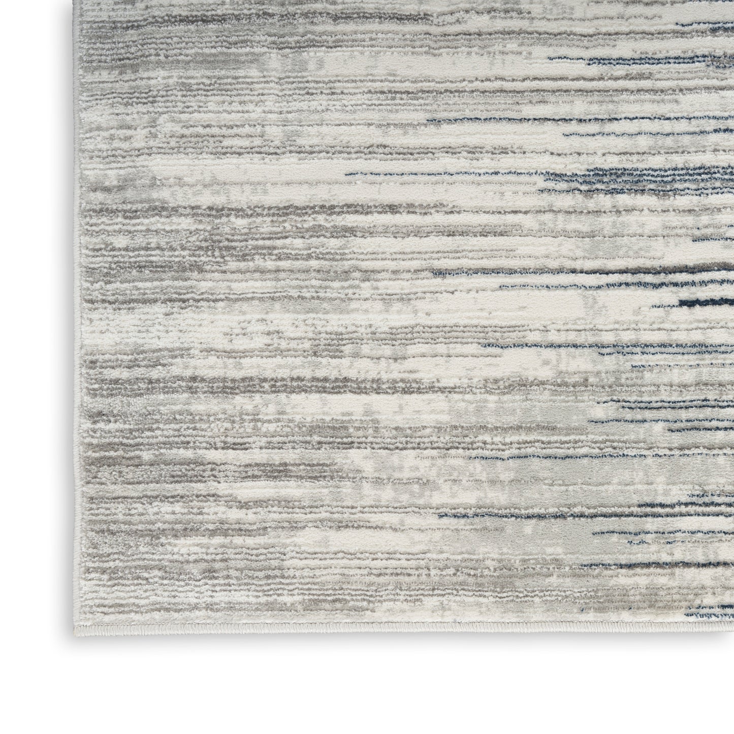 Rectangular area rug with soft gray, cream and blue brushstroke stripes; low-pile, textured design, corner view.