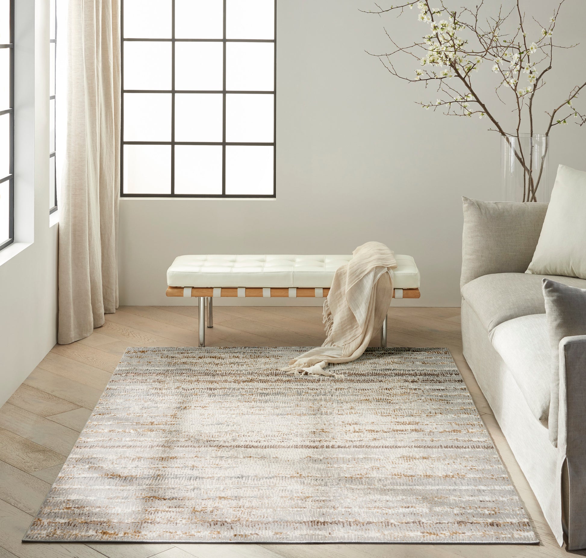 Neutral rectangular area rug with subtle beige-gray pattern in a sunlit modern living room.