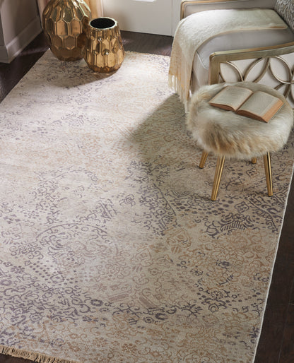 Cream ornate patterned area rug with taupe floral motifs; glam bedroom with gold metal bed frame, fur stool & gold vases.