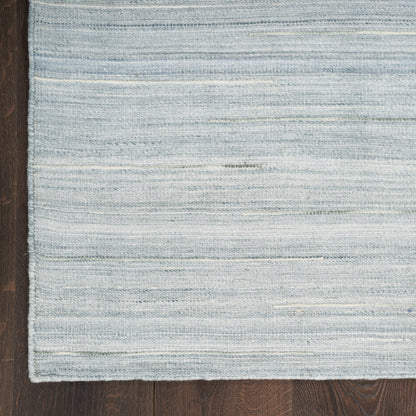 Light blue and white striped woven rug on dark wood floor; rectangular with a soft, textured weave.