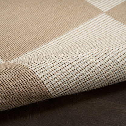 Beige & cream striped woven rug with rolled edge on dark wood floor.