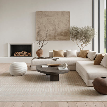Neutral living room with beige sectional, round dark wood coffee table, beige rug, potted trees, and a modern fireplace.