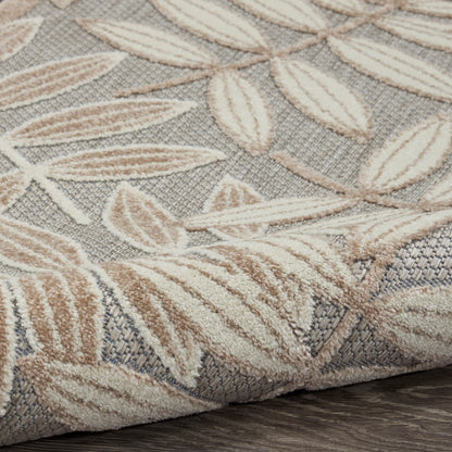Beige leaf-patterned woven rug with textured pile & folded edge on dark wood floor.