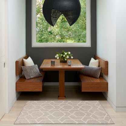 Wooden corner dining nook with benches, rectangular table, dark gray wall, sculptural black pendant light, white flowers centerpiece, beige geometric rug.