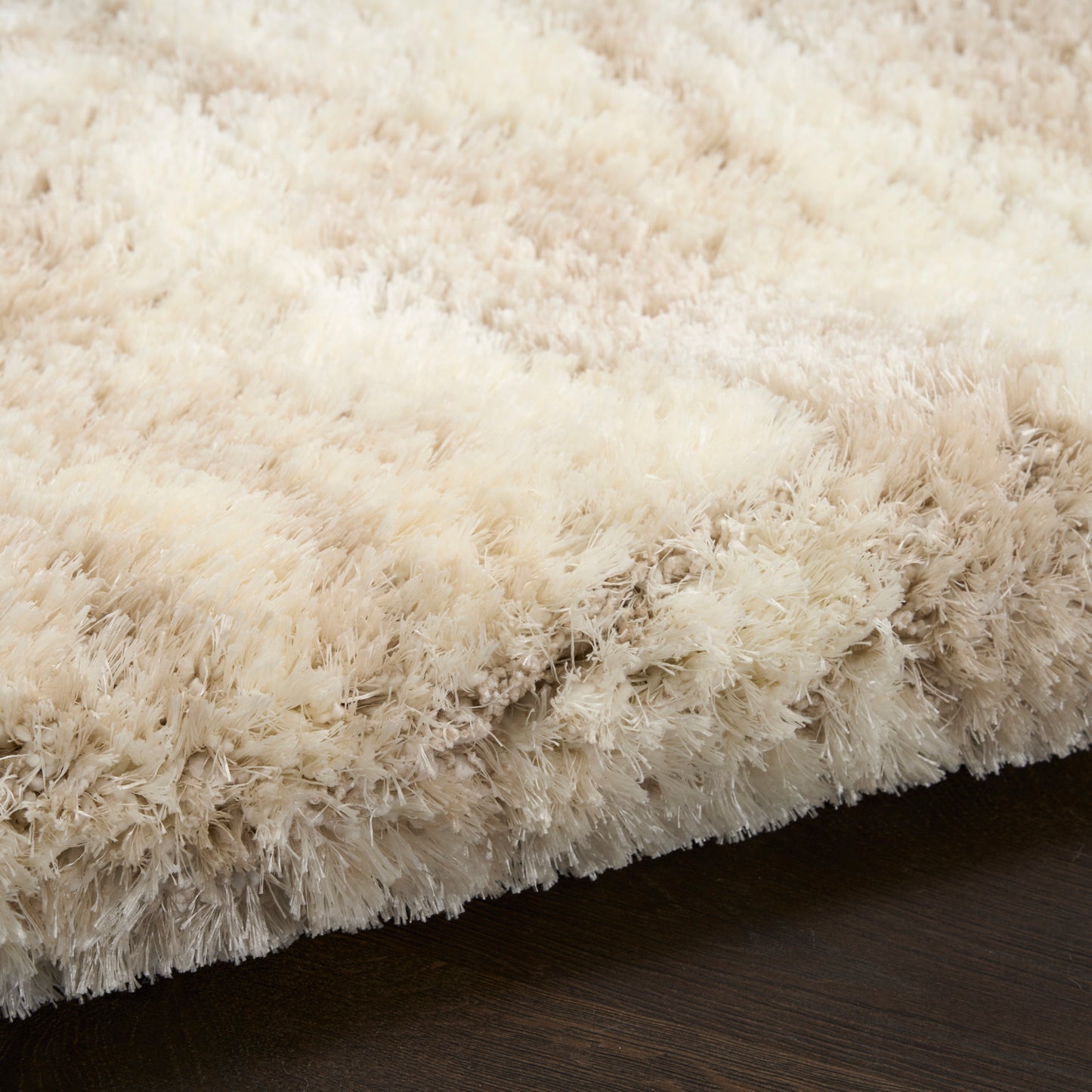 Ivory cream shag rug with dense fluffy high-pile texture on dark wood floor.