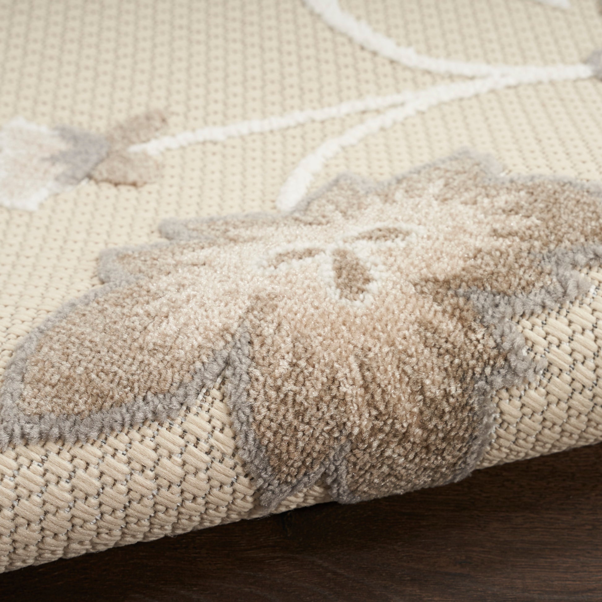 Beige woven rug with cream floral/star motif and soft raised pile for natural, textured floor decor.