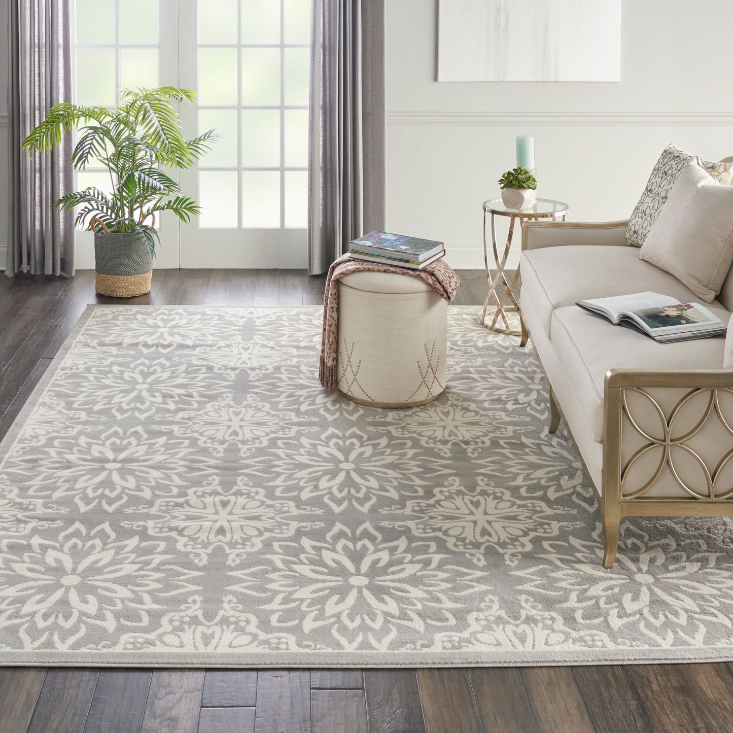 Rectangular woven area rug with ivory floral motif on gray, in a modern glam living room.