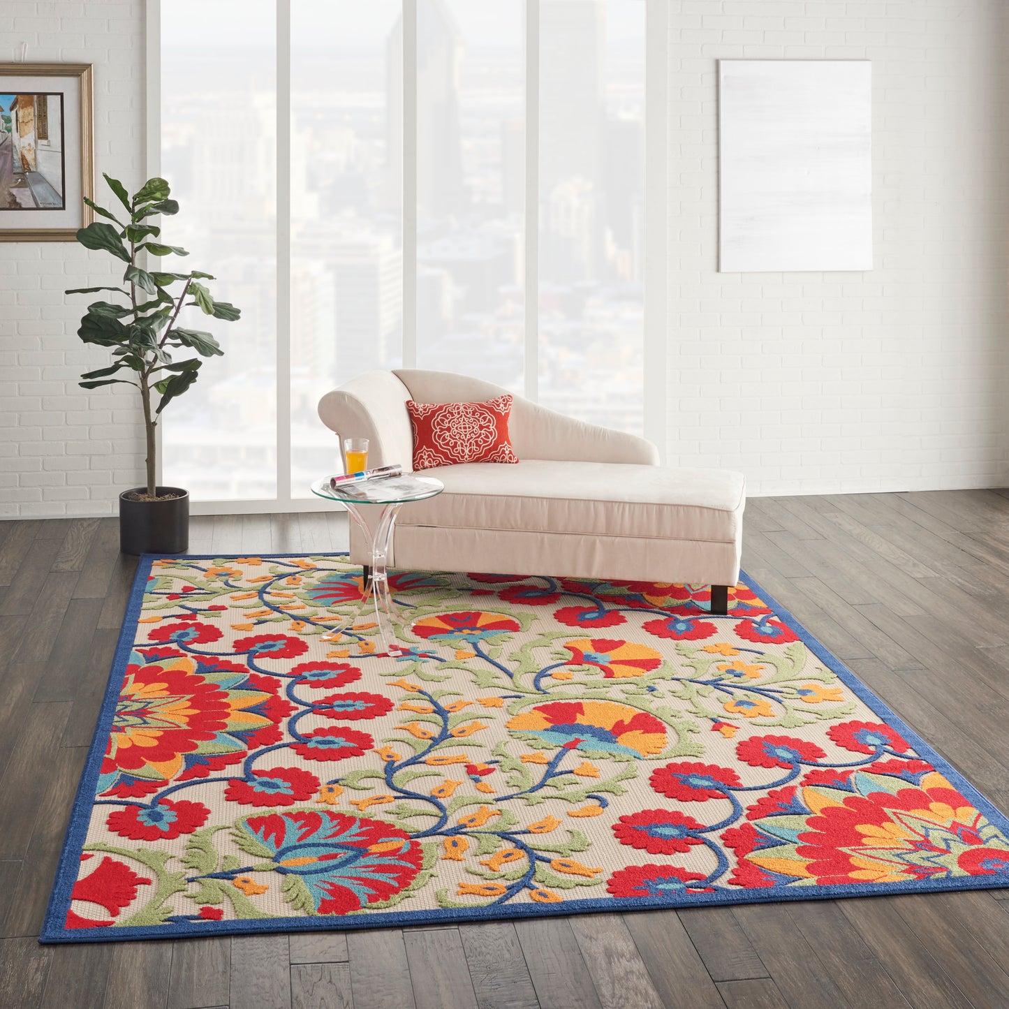 Bright living room with a floral rug: cream background, red & yellow flowers, blue border; cream chaise & red cushion.