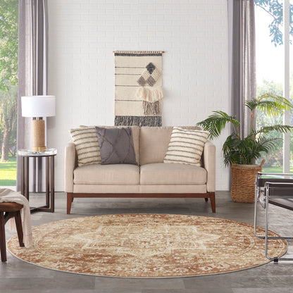 Beige fabric sofa with wood legs and two decorative pillows, in a bright living room with a round tan rug and woven wall art.