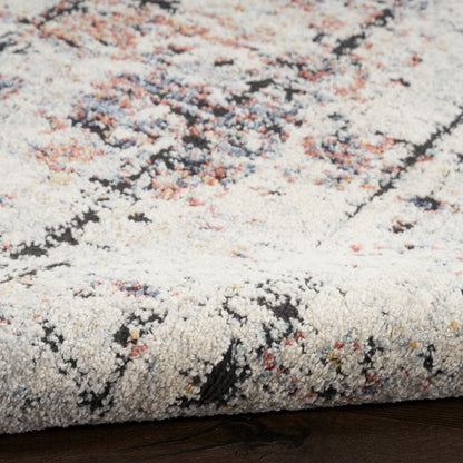 Cream textured rug with abstract multicolor pattern (pink, blue, orange, black); plush cut-pile and rolled edge.