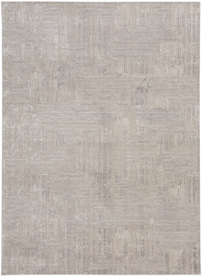 Rectangular beige area rug with cream-toned geometric patchwork and subtle linear textures.