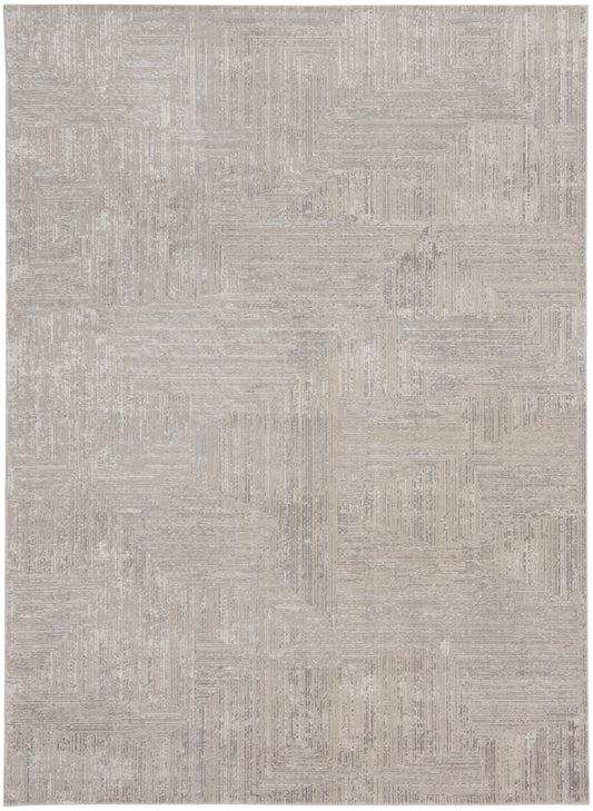 Rectangular beige area rug with cream-toned geometric patchwork and subtle linear textures.