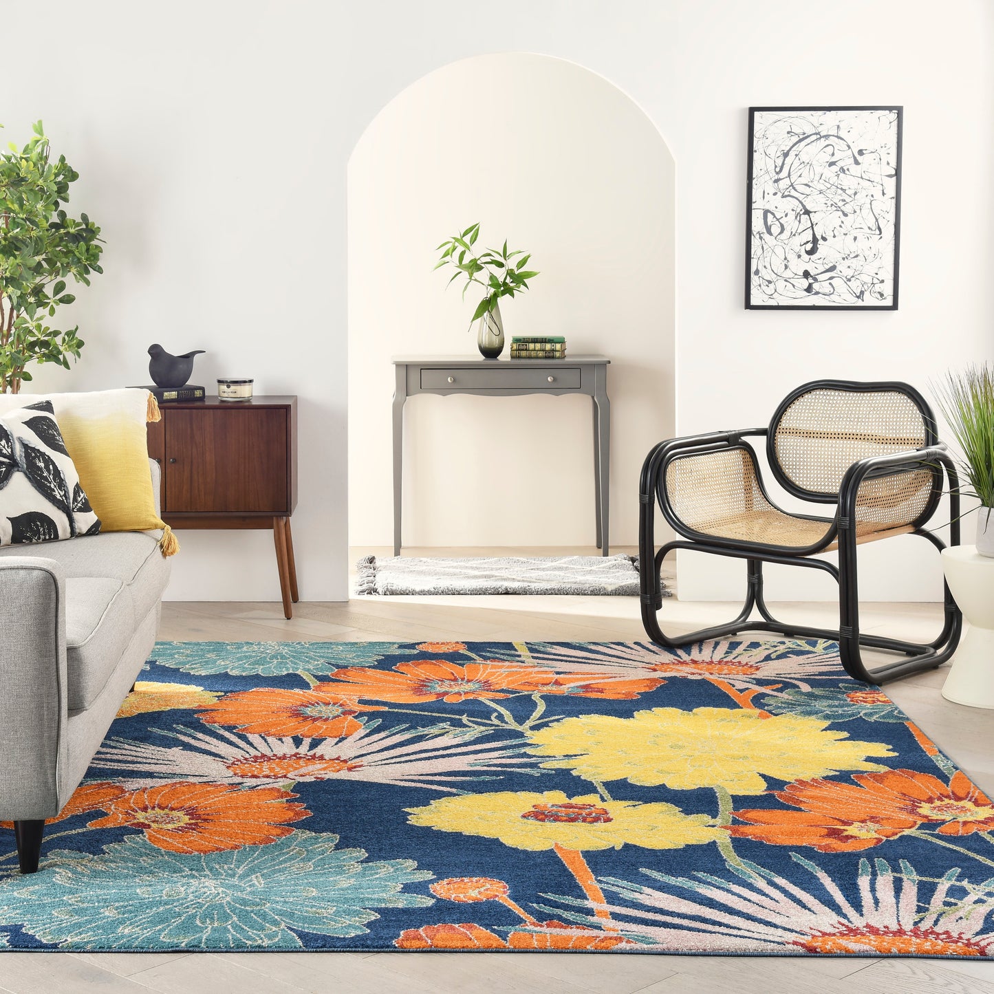 Bright living room with arched alcove, colorful floral rug, gray sofa, black-rattan chairs, and a console table.