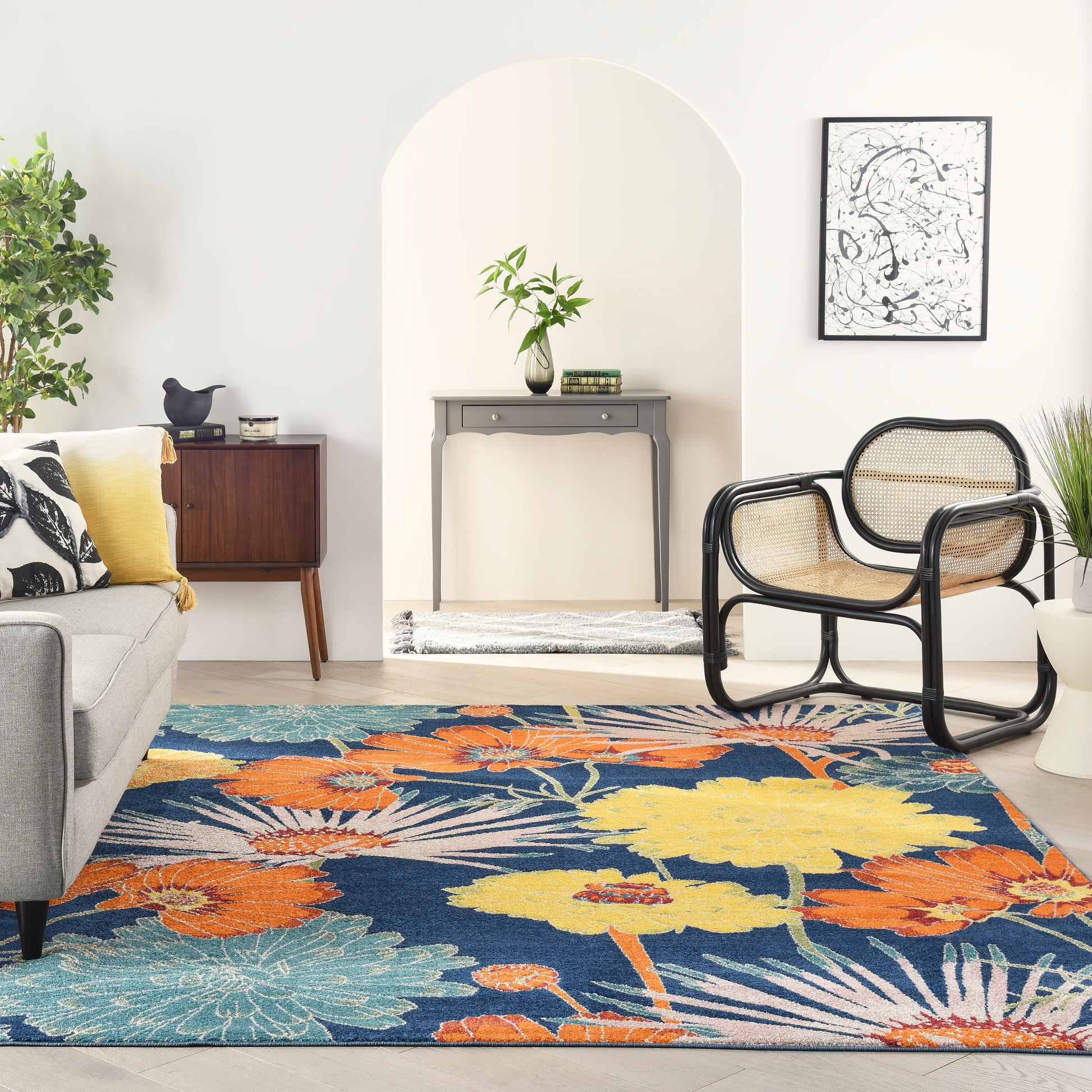Bright living room with arched alcove, colorful floral rug, gray sofa, black-rattan chairs, and a console table.