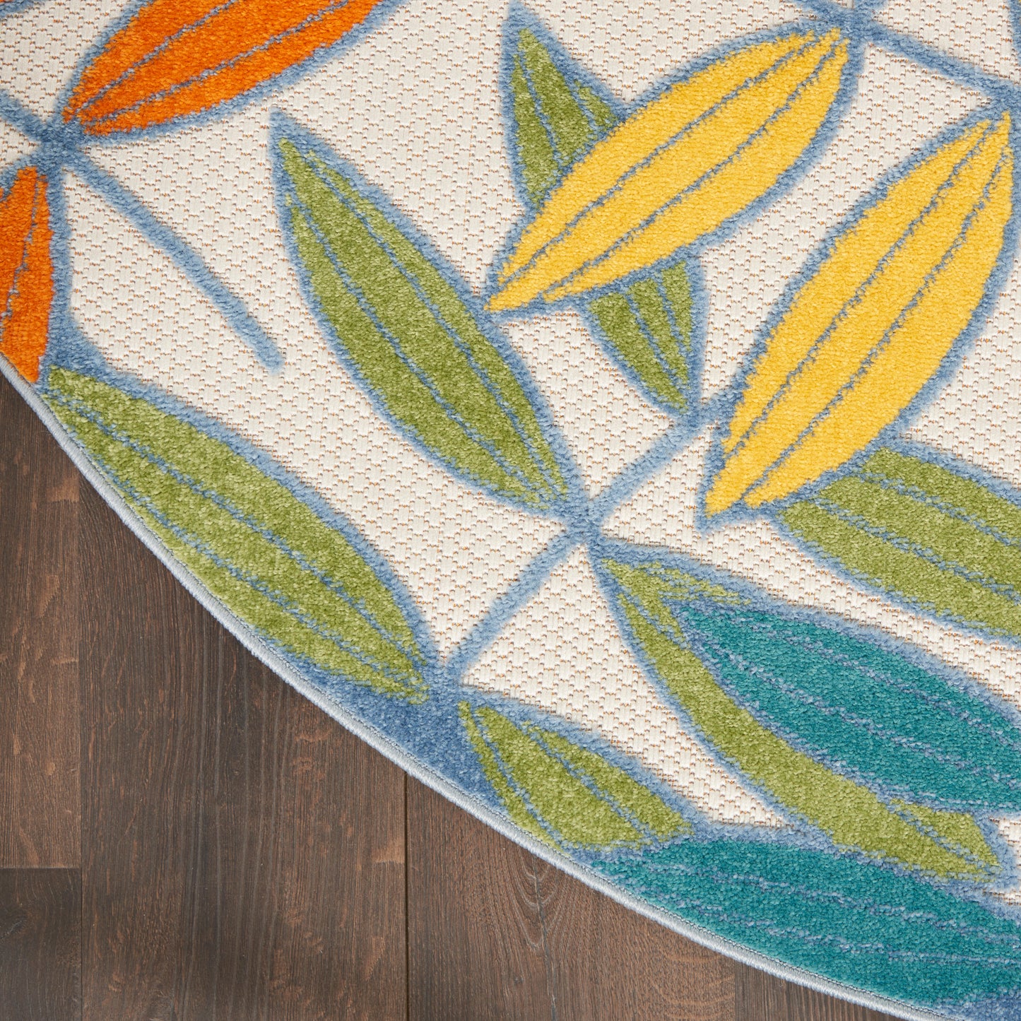 Round rug with bold leaf pattern in yellow, green, teal and orange on a light beige weave, bordered with blue lines.