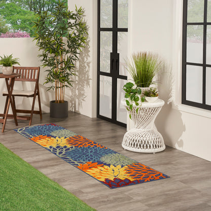 Vibrant tropical leaf runner rug on wood floor beside glass doors; orange, blue, yellow leaves.