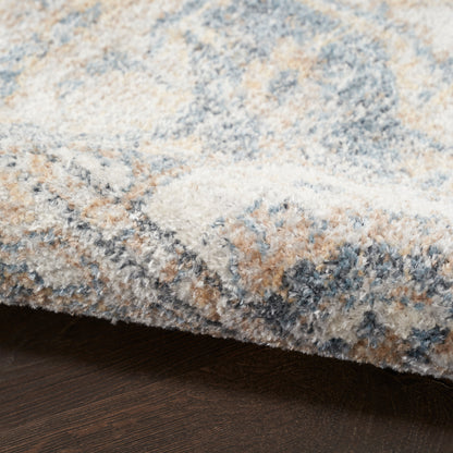Soft, plush shag rug in blue, beige, cream and gray tones with a mottled abstract pattern on a dark wood floor.
