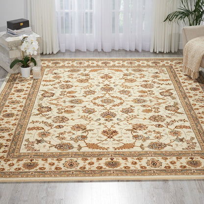 Beige oriental-style area rug with brown and gold floral motifs and a decorative border in a bright living room.