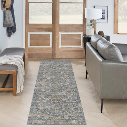 Blue-gray woven runner rug with beige pattern down a wooden hallway, flanked by a gray sofa and bench with throws.