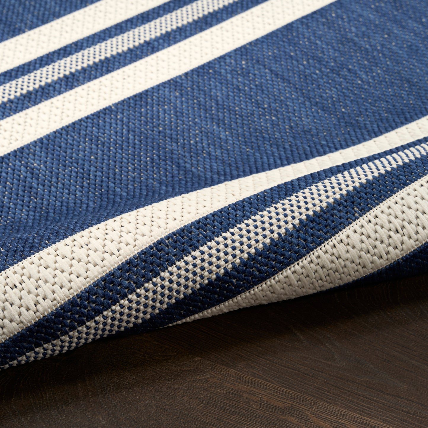 Navy blue and white striped rug runner, textured woven fibers with bold stripes, close-up.