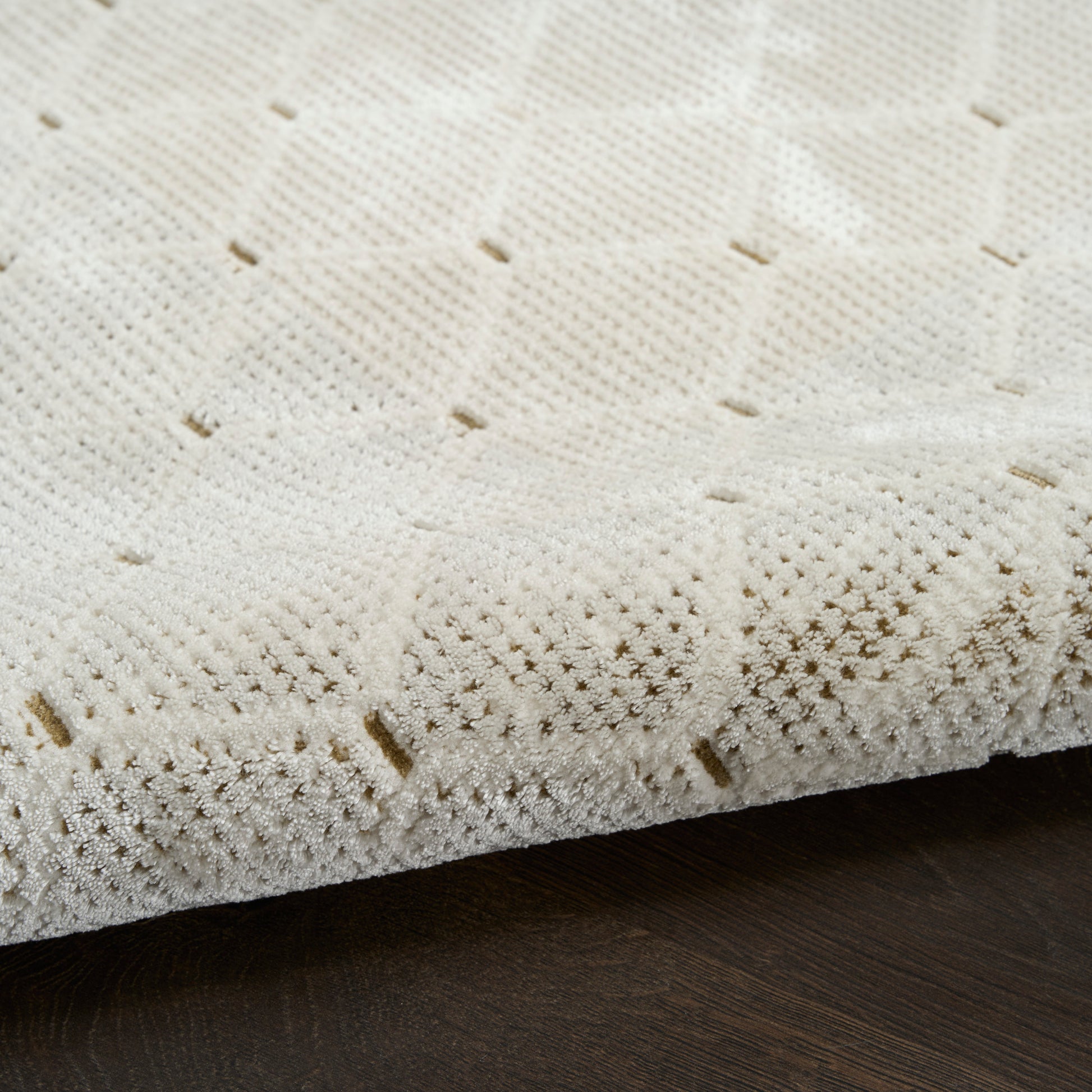 Cream crochet-knit rug with square lattice pattern on dark wood floor.