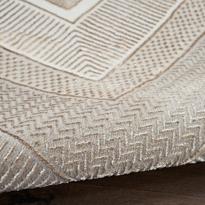 Beige woven area rug with geometric chevron & stripe patterns on dark wooden floor.