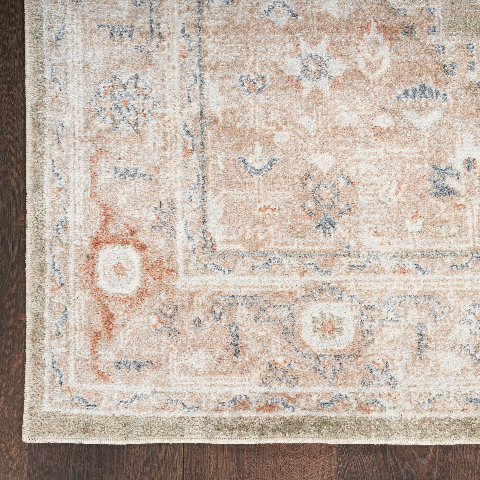 Beige oriental rug with blue floral accents and a pale border on dark wooden floor.