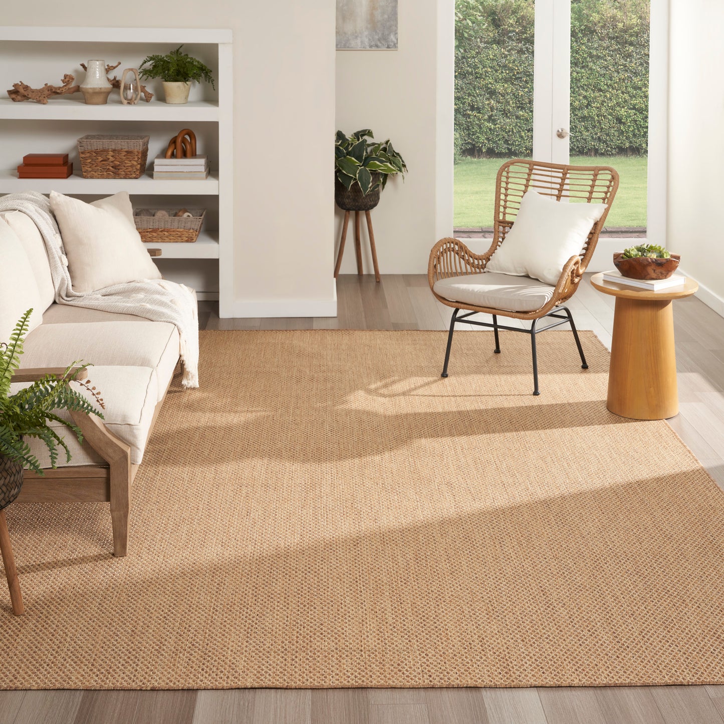 Natural jute rectangular rug in warm beige, woven texture, pairing with cream sofa and wicker chair in a cozy living room.