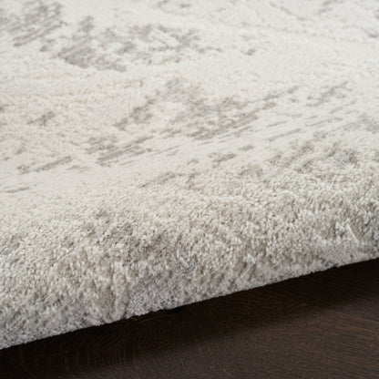 Cream high-pile shag rug with subtle gray pattern, plush texture, edge resting on dark hardwood floor.