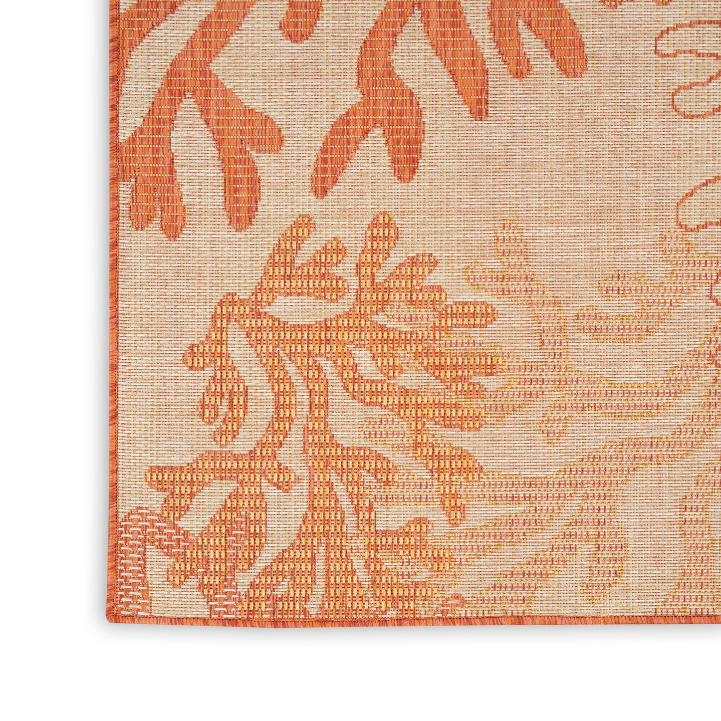 Close-up corner of orange floral tapestry rug; peach-beige woven background with bold orange botanical pattern and border.