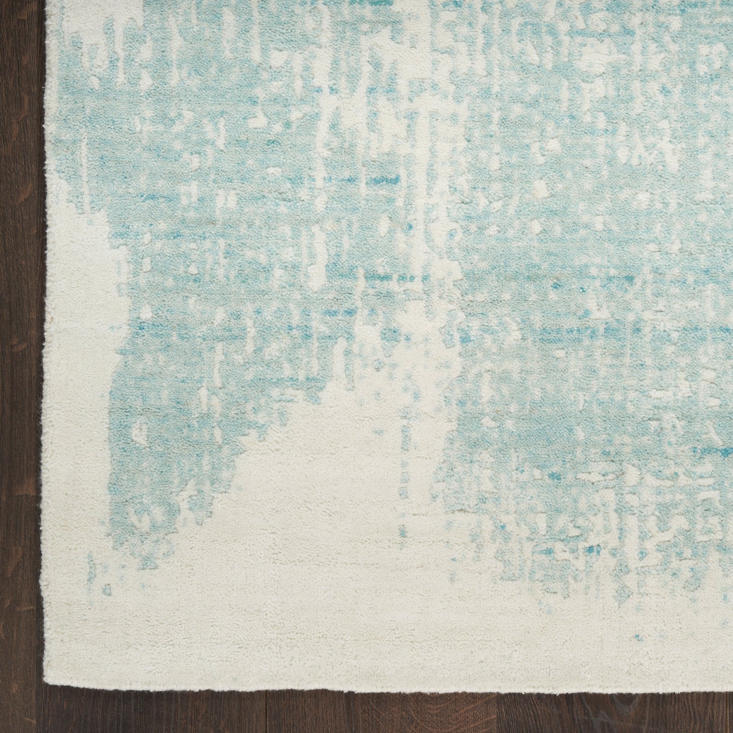 Blue and ivory distressed rectangular rug with abstract pattern on dark wood floor.