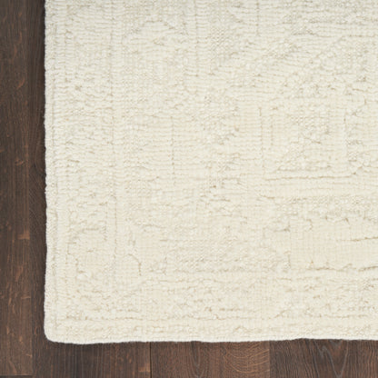 Plush cream area rug with a subtle geometric border on dark hardwood floor.