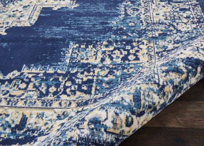 Blue distressed oriental rug with cream geometric motifs, curled edge on dark wood floor