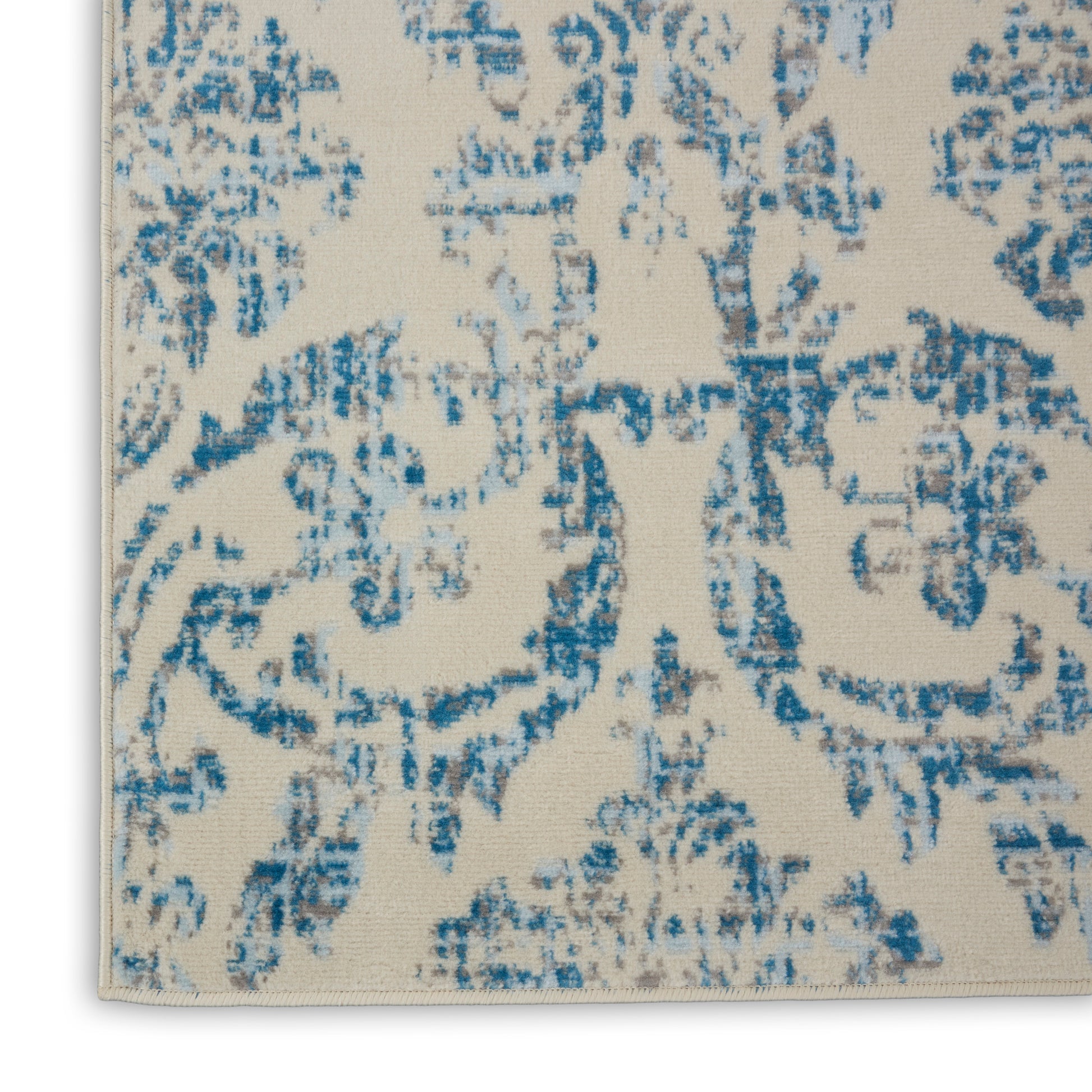 Rectangular beige area rug with a blue distressed damask pattern; woven textile for living room decor.