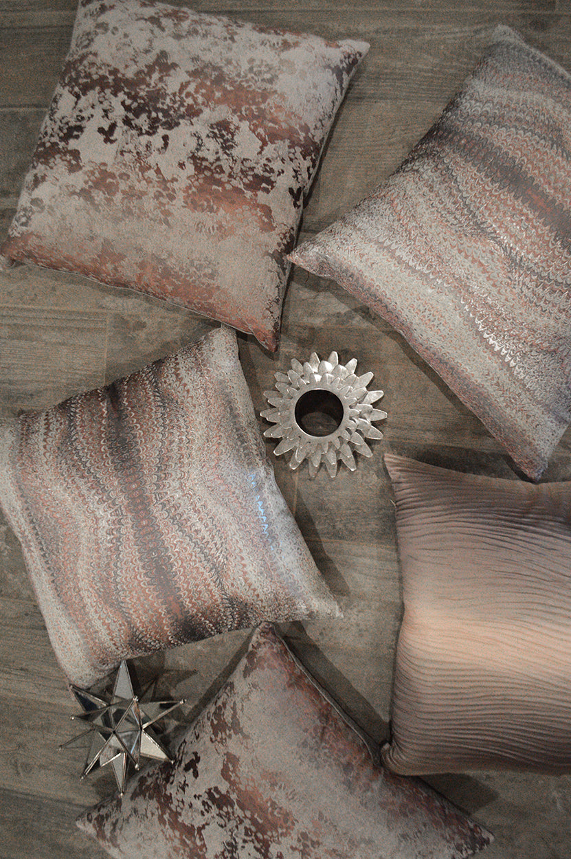 Decorative throw pillow in pink textured velvet/sequin finish, displayed on a wooden floor.