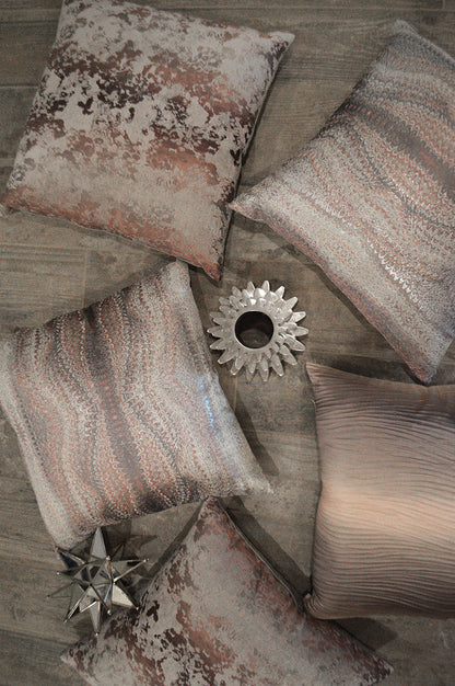 Decorative throw pillow in pink textured velvet/sequin finish, displayed on a wooden floor.