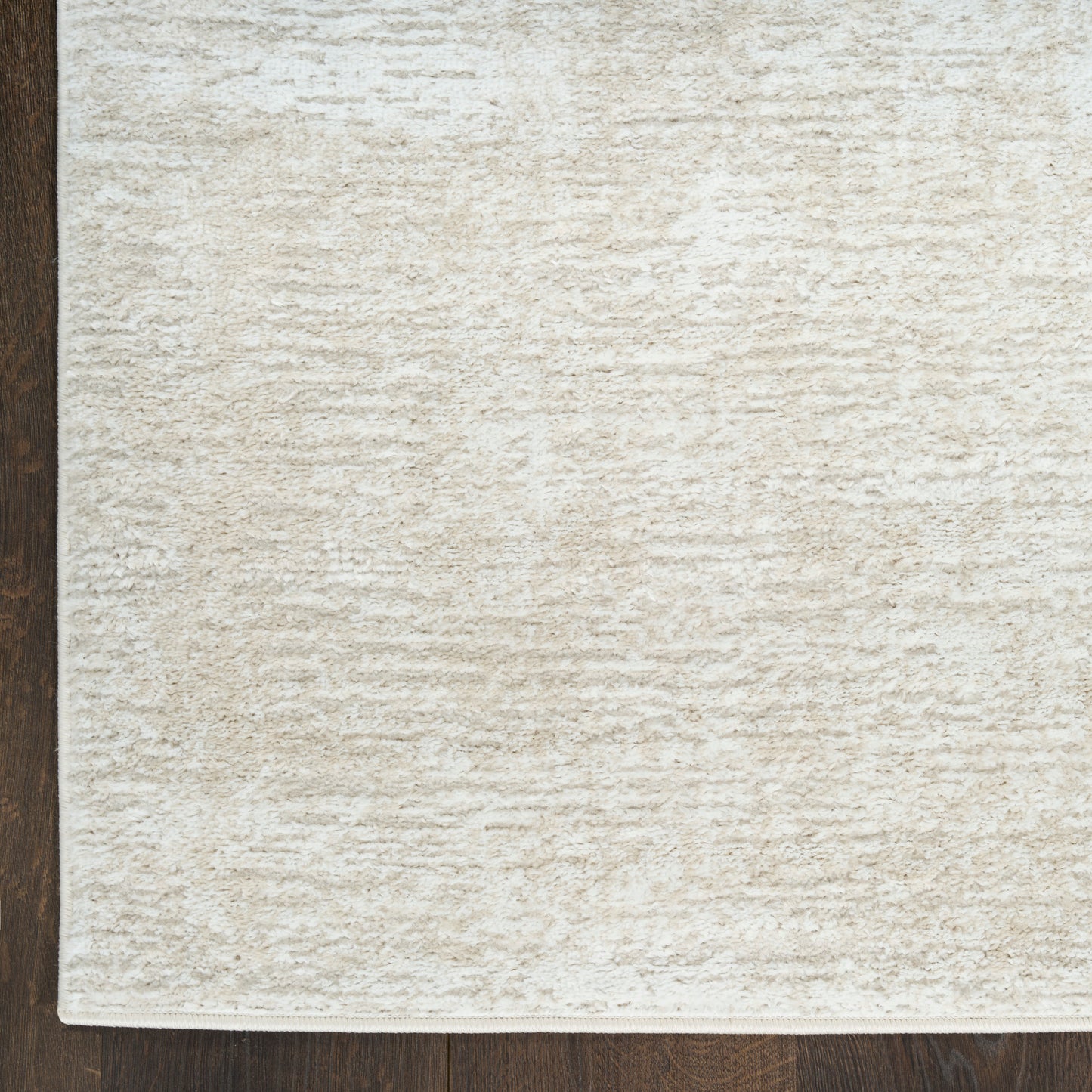 Cream textured rug with soft, dense pile on dark wood floor; neutral beige, rectangular shape.
