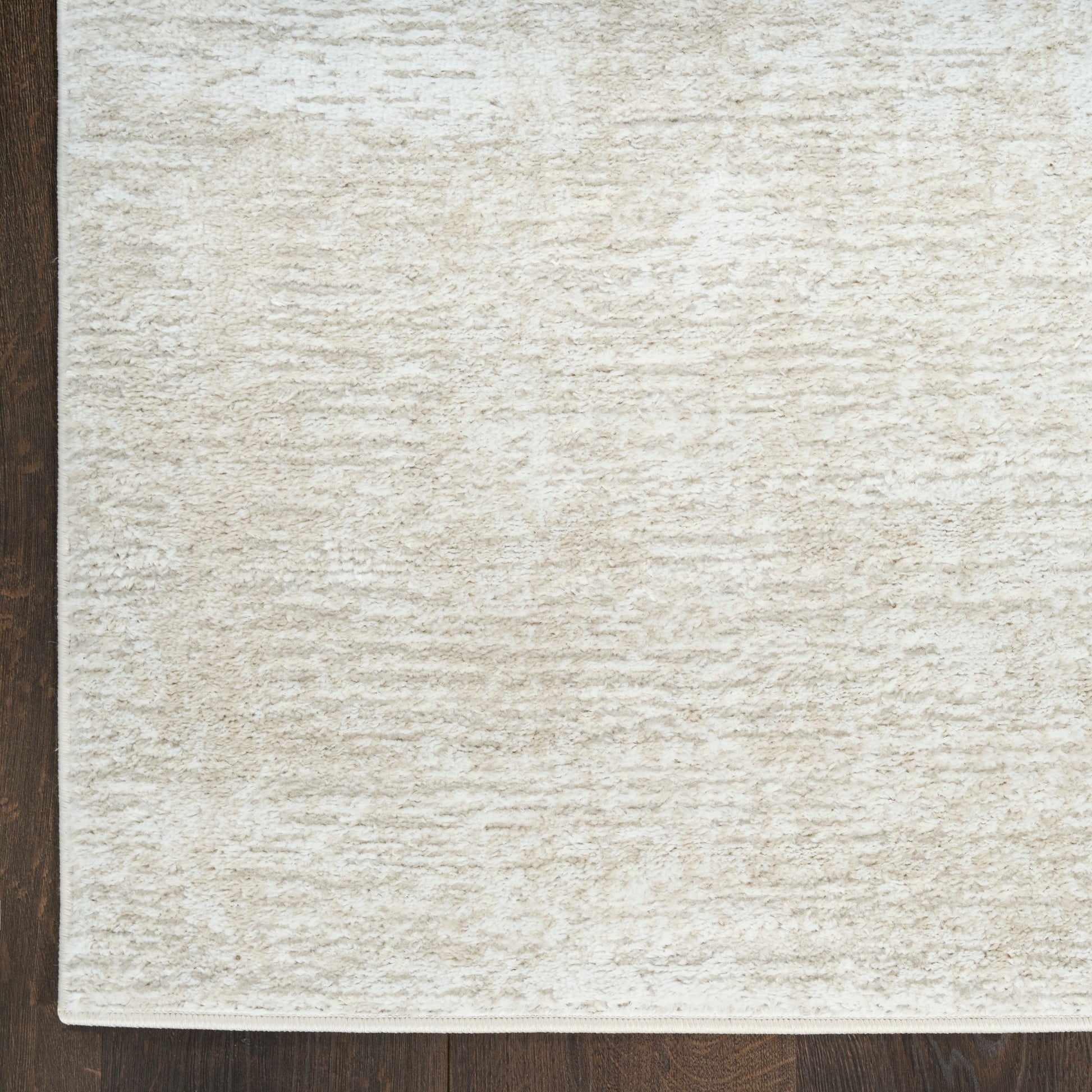 Cream textured rug with soft, dense pile on dark wood floor; neutral beige, rectangular shape.