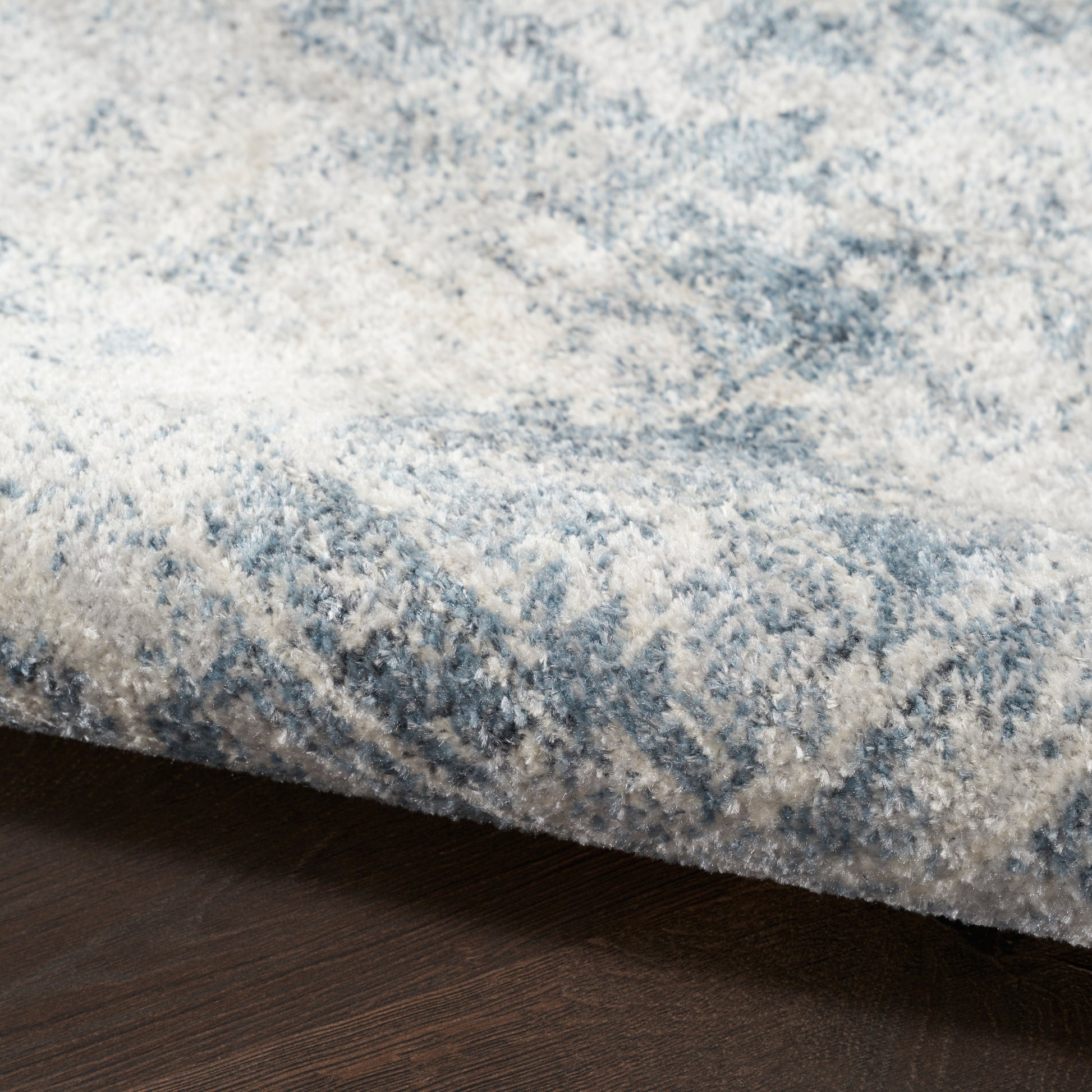 Blue and white marbled plush area rug with soft pile on dark wood floor.