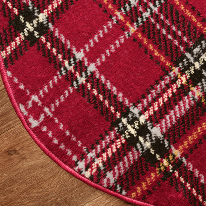 Red plaid Christmas round rug with black, white and yellow stripes, pink edging, fuzzy wool texture on wood floor.