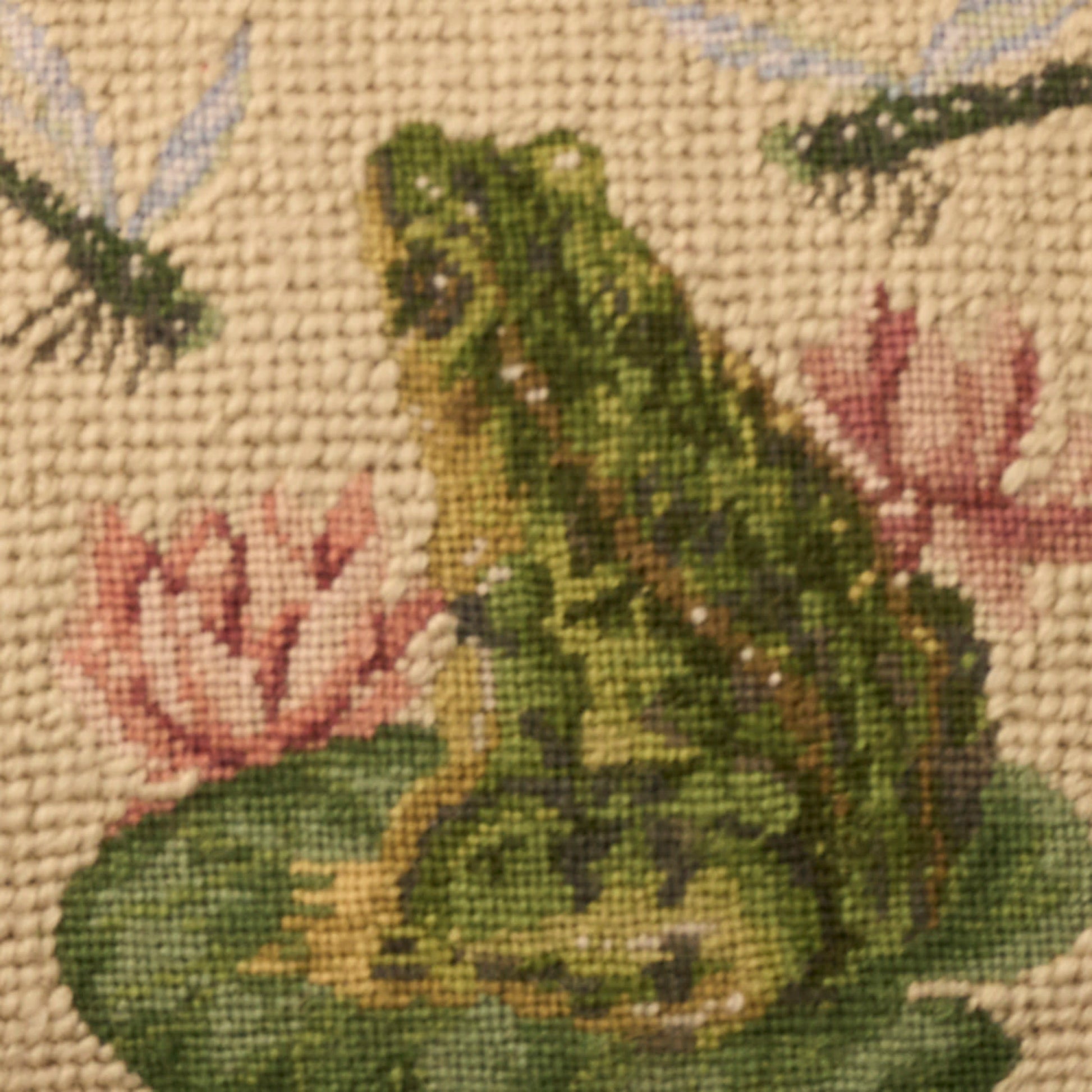Tapestry textile with a green frog on a lily pad among pink flowers, beige woven background; rustic home decor.