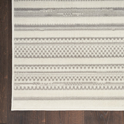 Rectangular beige and gray flat-weave rug with geometric striped patterns on a dark wood floor.