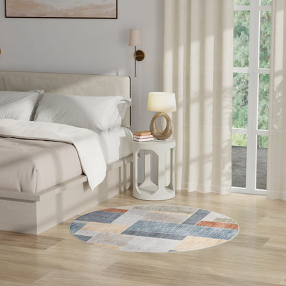 Neutral bedroom with beige bed, round rug in blue/gray/orange, white circular nightstand and lamp, sheer curtains.