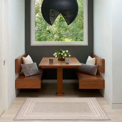 Cozy corner dining set with wood benches, rectangular table, black curved pendant, vase of white flowers, gray wall and rug