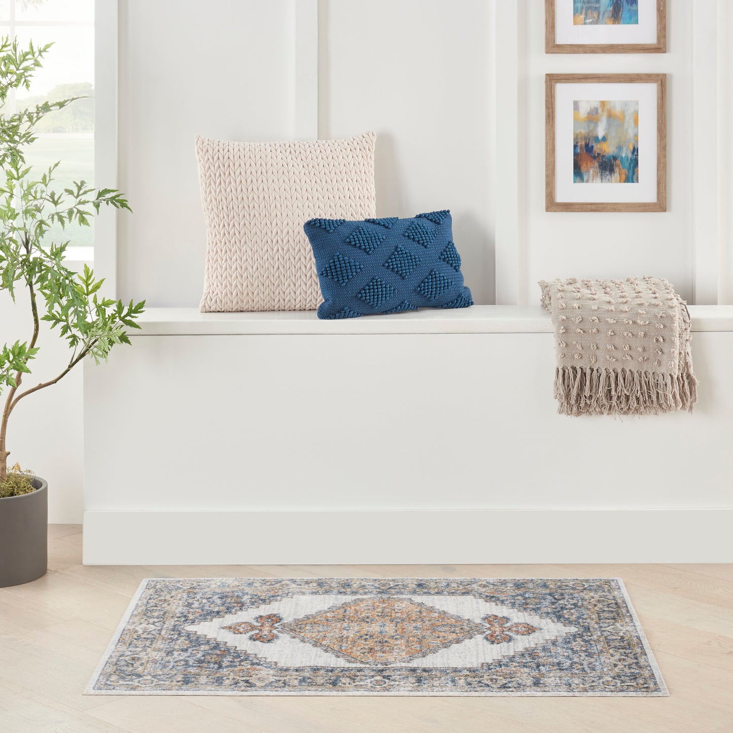 Blue-gray diamond rug 2' x 4' with a beige fringed throw, beige knitted cushion, and a blue textured cushion nearby.