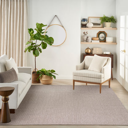 Neutral living room with cream sofa, beige armchair, circular wall hoop, large potted plant, woven basket, light wood shelves