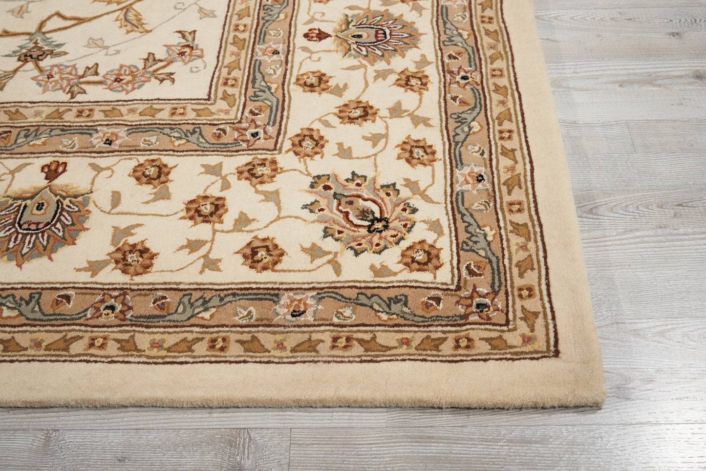 Cream oriental area rug, 9' x 12', with floral motifs in brown, blue, and rust, bordered trim on light wood floor.