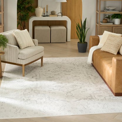 Ivory patterned area rug in a modern living room with beige fabric armchair, tan leather sofa, wood accents, and greenery.